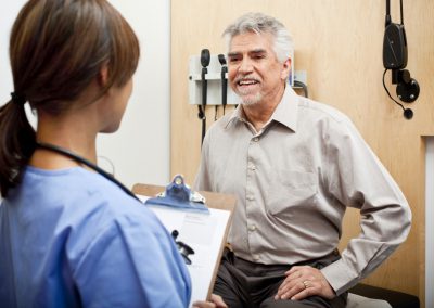 Happy patient on exam table talking with health professional